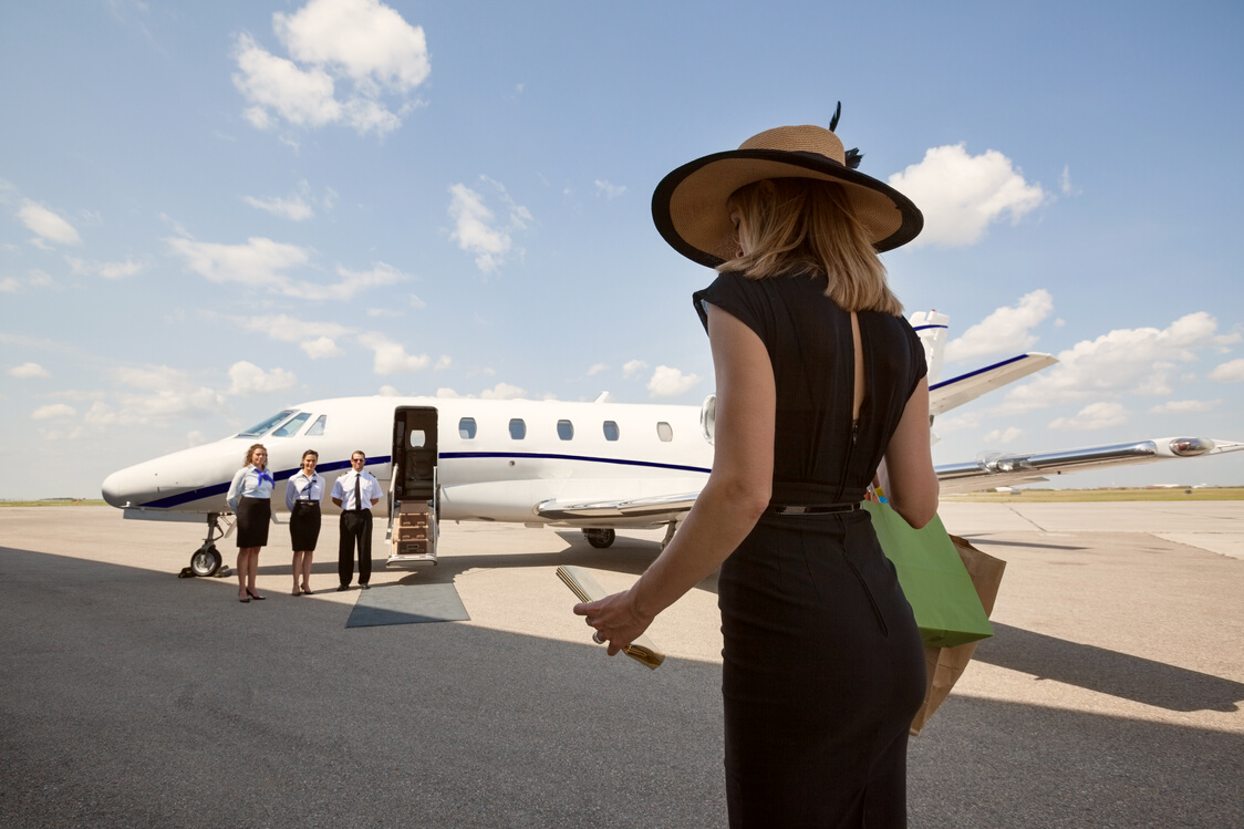 Woman Walking towards Pilot and Stewardesses against Private Jet